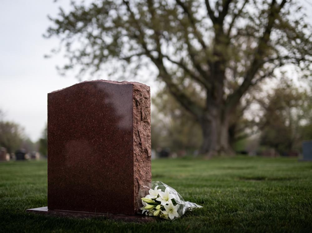 Polished granite upright headstone with flowers in a cemetery